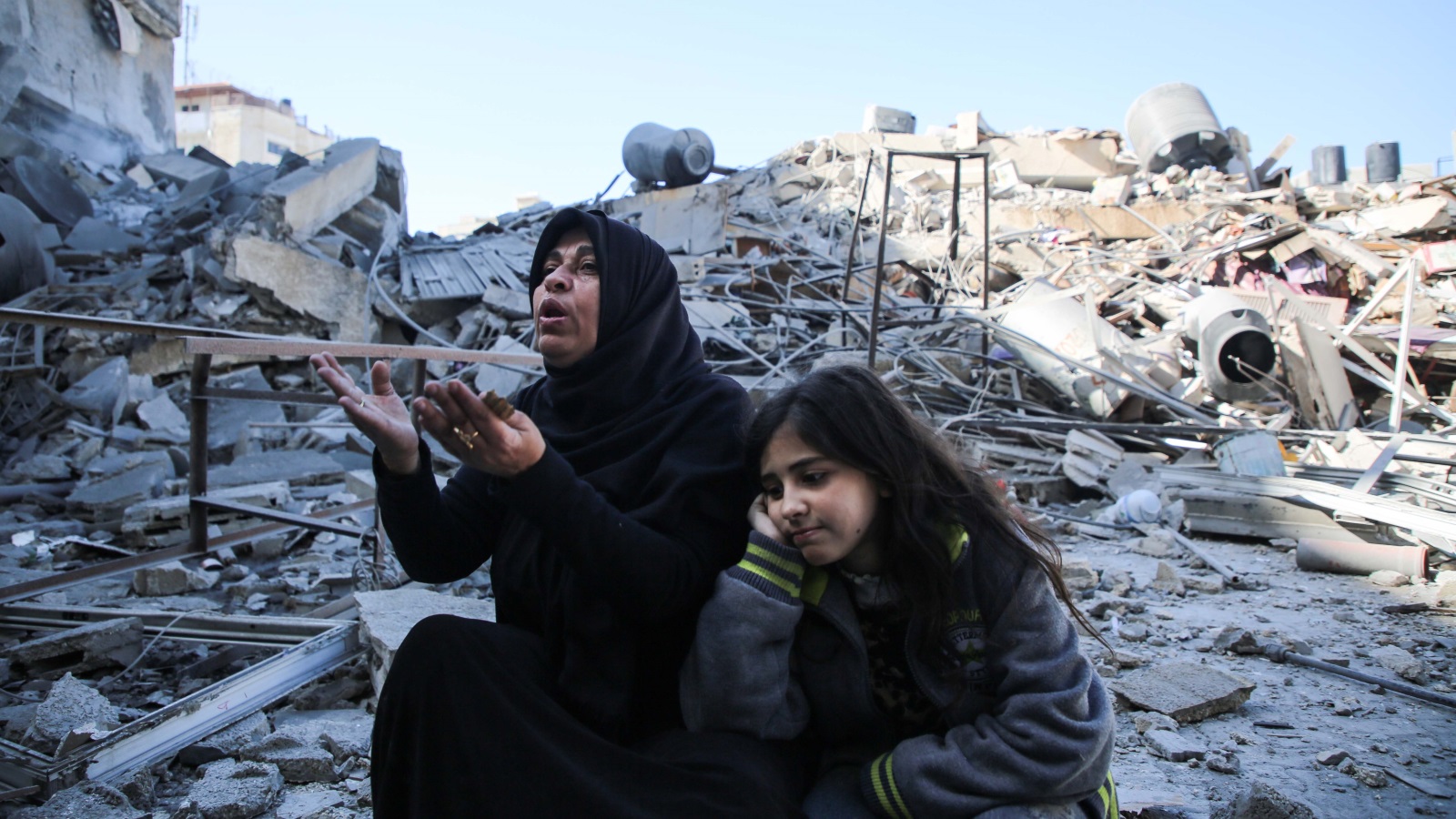 ‪سيدة فلسطينية فوق أنقاض بناية سكنية دمرها القصف الإسرائيلي في حي الرمال بمدينة غزة‬ (الأناضول)