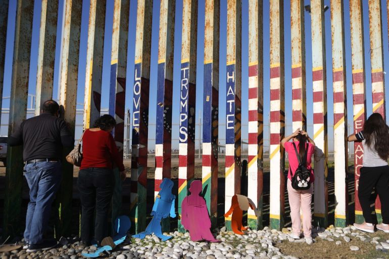 TIJUANA, MEXICO - DECEMBER 15: Sisters Fernanda and Evelyne Lopez (R) look toward their father standing in San Diego on the other side of the U.S.-Mexico border fence during the 'Posada Without Borders' event on December 15, 2018 in Tijuana, Mexico. The binational Christmas event is held with religious leaders and faithful on both sides of the fence, allowing loves ones to sometimes view family members living on the other side. This year family members and others were