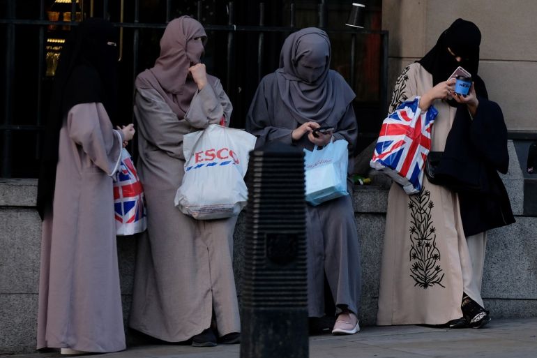 A group of Muslim women check their mobile telephones as they wait outside Westminster tube station in London, Britain August 28, 2018. REUTERS/Phil Noble