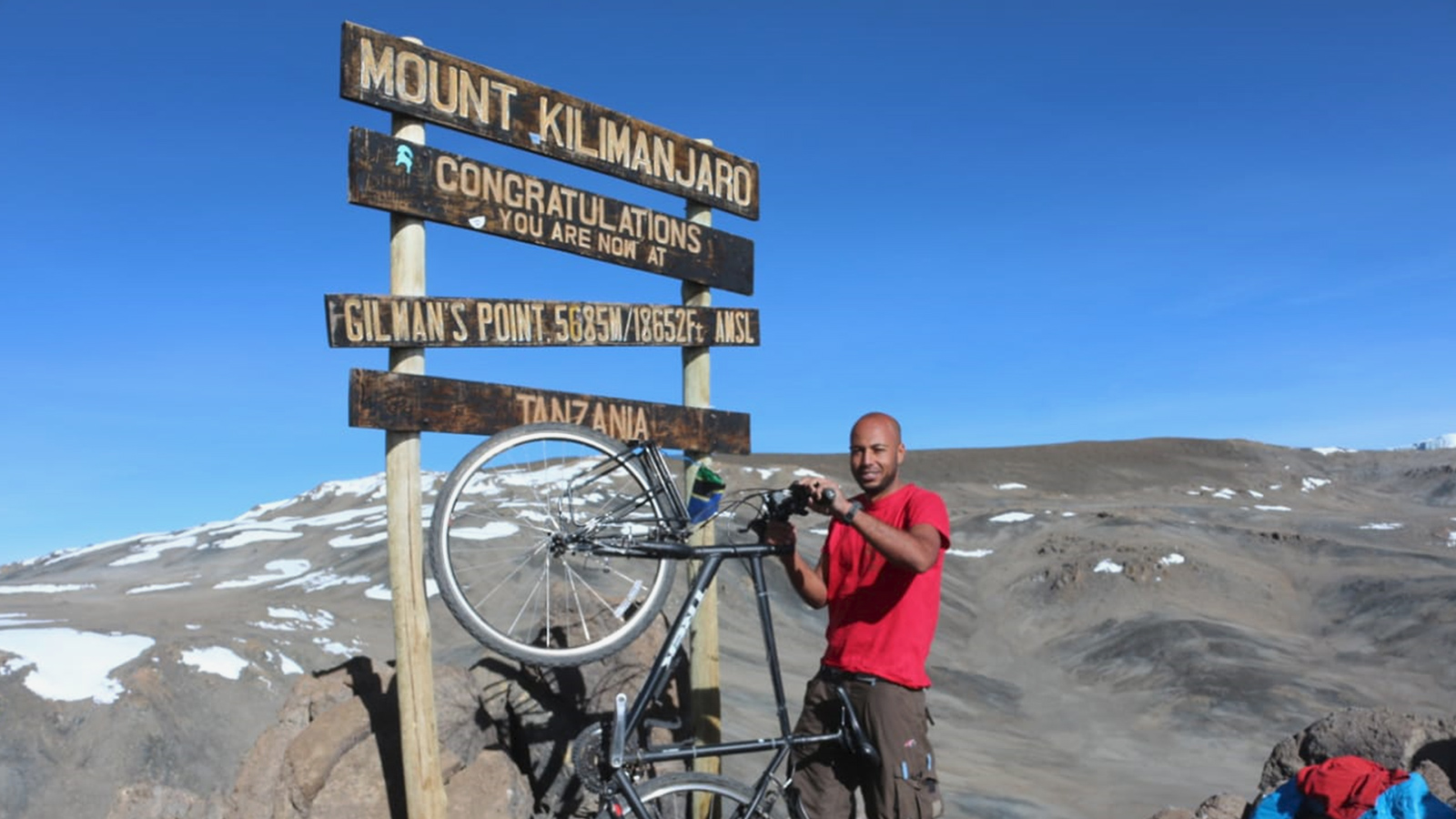 ‪ياسين مع دراجته بأعلى قمة بأفريقيا‬ (الجزيرة)