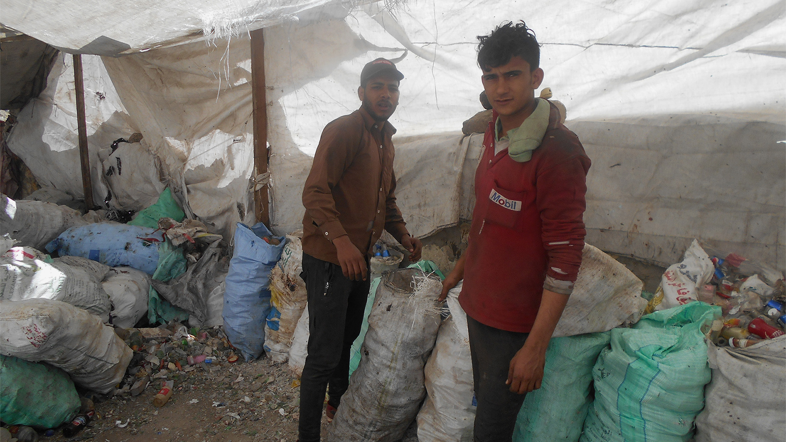 ‪شابان يعملان على فرز النفايات في حي الزبالين استعدادا لإعادة تدويرها‬ (الجزيرة)