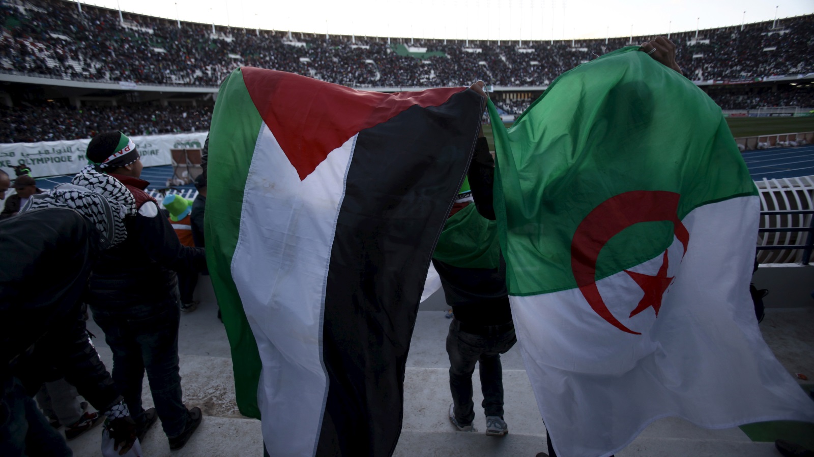 عَلَما فلسطين والجزائر خلال مباراة سابقة بين منتخبي البلدين في عام 2016 (رويترز)