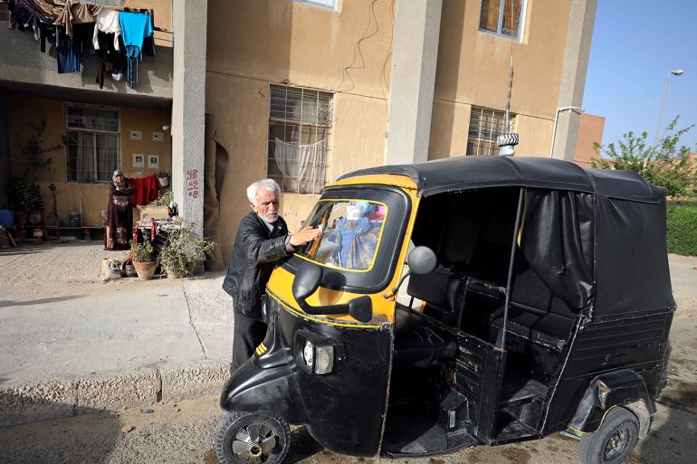 Syrian refugee Ahmad al-Khatib cleans his auto rickshaw as his wife Ilham Mohammad watches, outside their home in Cairo