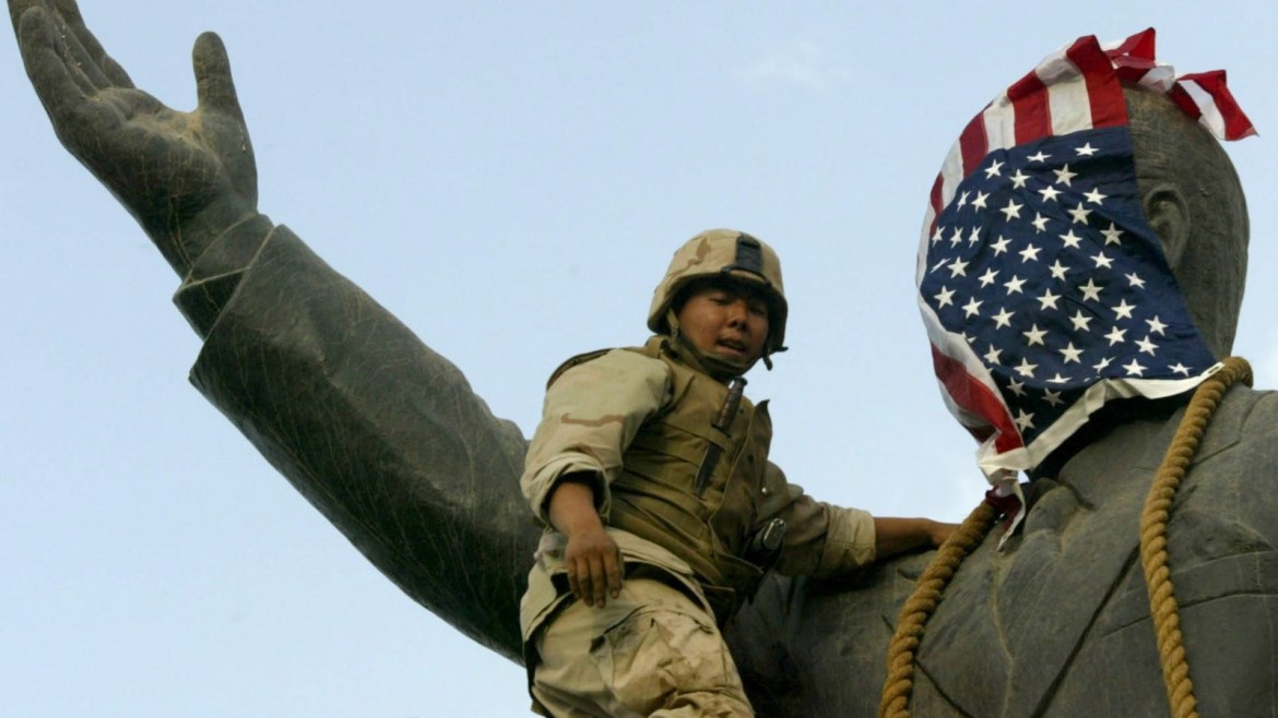 A U.S. Marine covers the face of a statue of Iraqi President Saddam Hussein with a U.S. flag in Baghdad April 9, 2003. U.S. troops briefly draped an American flag over the face of a giant statue of President Saddam Hussein in central Baghdad on Wednesday as they prepared to topple it in front of a crowd of Iraqis.The gesture, likely to be highly provocative in much of the Arab world where the U.S. invasion of Iraq has stirred widespread anger, was quickly reversed and a