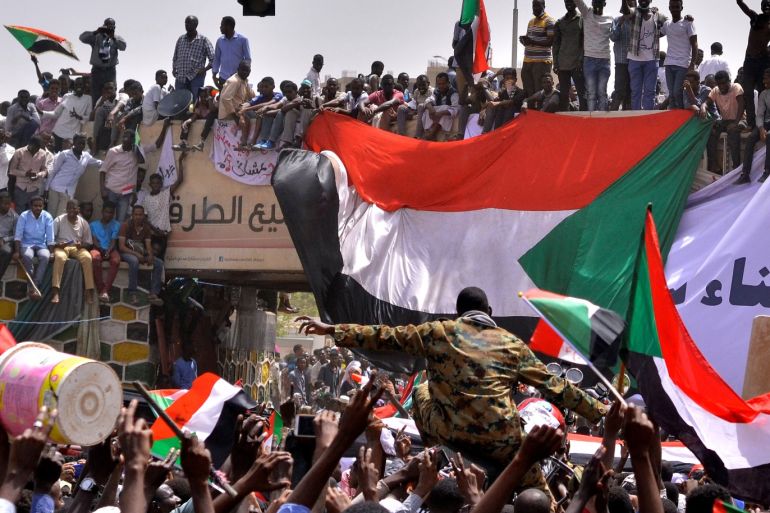 A military officer is carried by the crowd as demonstrators chant slogans and carry their national flags, after Sudan's Defense Minister Awad Mohamed Ahmed Ibn Auf said that President Omar al-Bashir had been detained