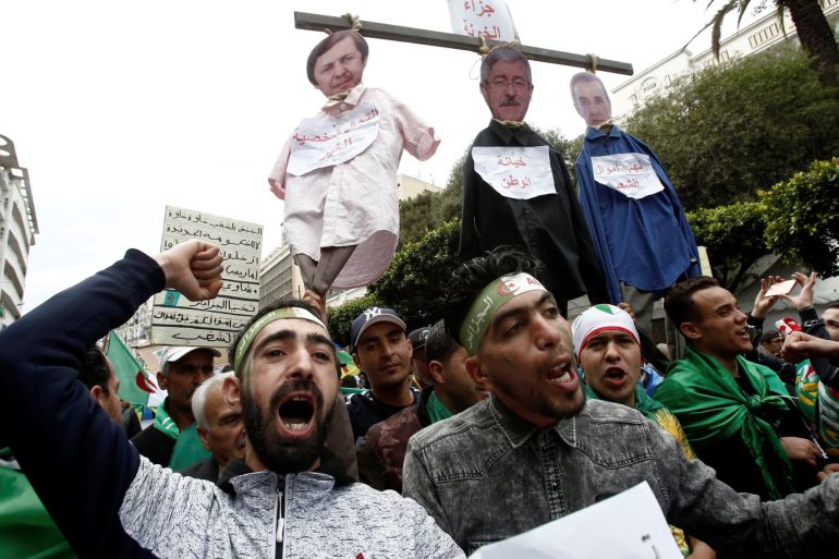 People gesture and carry a mock hangman with the faces of Algerian businessman Ali Haddad, former prime minister Ahmed Ouyahia, and Said Bouteflika, brother of former Algerian president Abdelaziz Bouteflika, during a protest to push for the removal of the current political structure, in Algiers, Algeria April 5, 2019. REUTERS/Ramzi Boudina