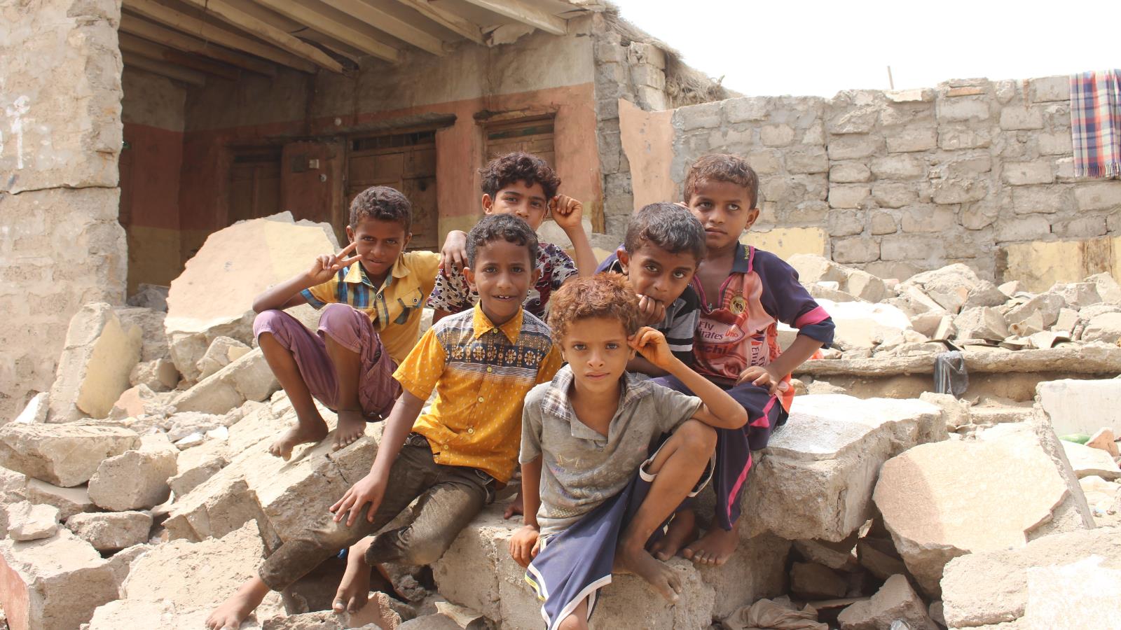 أطفال يمنيون يقفون على ركام منزل دمرته الحرب في الساحل الغربي لليمن(الجزيرة نت)