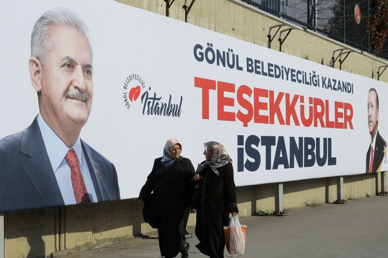 People walk past by AK Party billboards with pictures of Turkish President Tayyip Erdogan and mayoral candidate Binali Yildirim in Istanbul, Turkey, April 1, 2019. The billboards read: