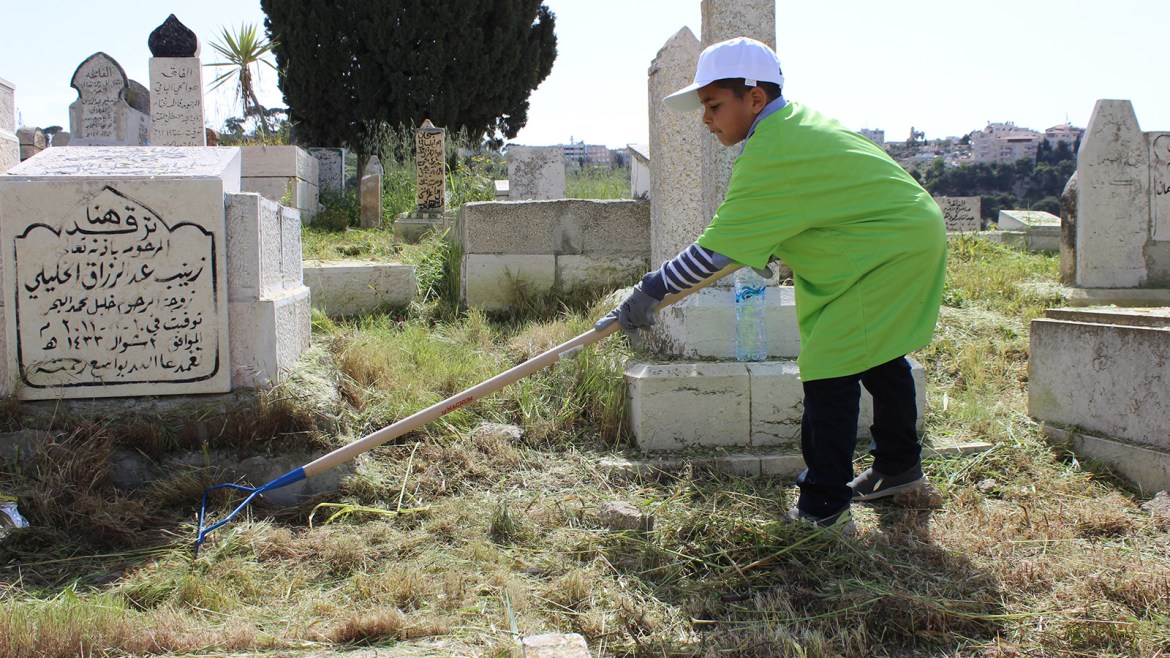 الطفل محمد ابو عجاج من بئر السبع خلال مشاركته في تنظيف مقبرة اليوسفية