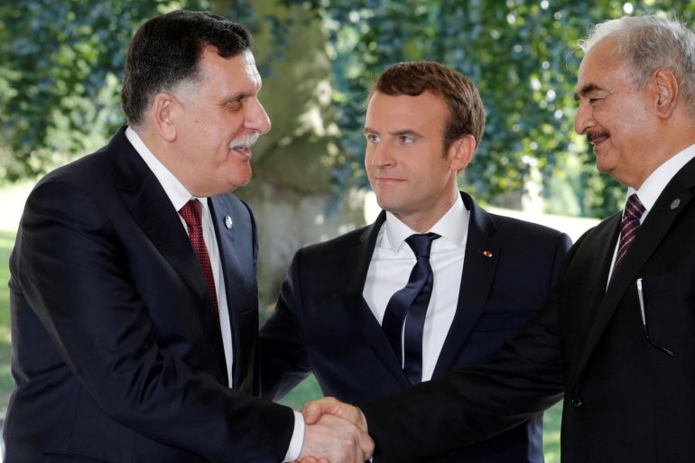 French President Emmanuel Macron stands between Libyan Prime Minister Fayez al-Sarraj (L), and General Khalifa Haftar (R), commander in the Libyan National Army (LNA), who shake hands after talks over a political deal to help end Libya’s crisis in La Celle-Saint-Cloud near Paris, France, July 25, 2017. REUTERS/Philippe Wojazer TPX IMAGES OF THE DAY