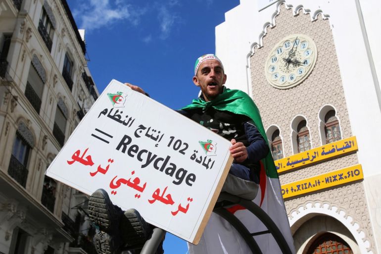 A man carries a banner during a protest to demand political change and the departure of the ruling elite in Algiers, Algeria April 12, 2019. The banner reads: