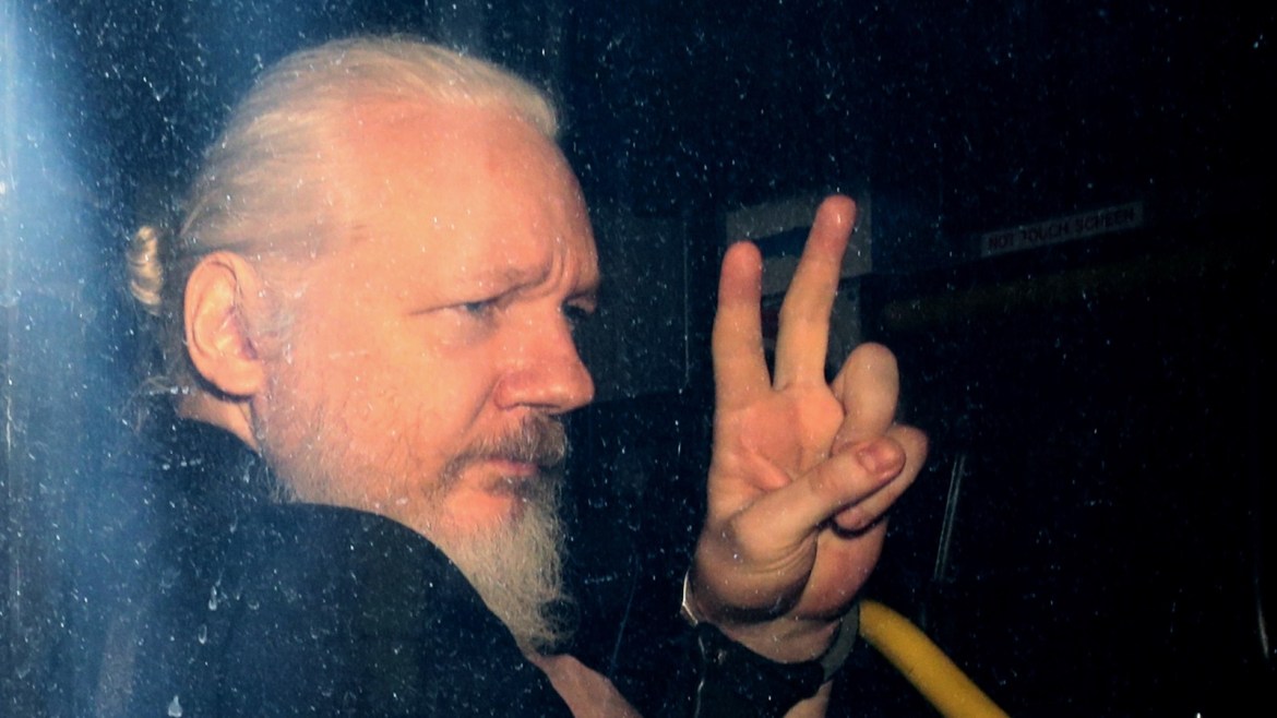 LONDON, ENGLAND - APRIL 11: Julian Assange gestures to the media from a police vehicle on his arrival at Westminster Magistrates court on April 11, 2019 in London, England.  After weeks of speculation Wikileaks founder Julian Assange was arrested by Scotland Yard Police Officers inside the Ecuadorian Embassy in Central London this morning. Ecuador's President, Lenin Moreno, withdrew Assange's Asylum after seven years citing repeated violations to international conventions. (Photo by Jack Taylor/Getty Images)