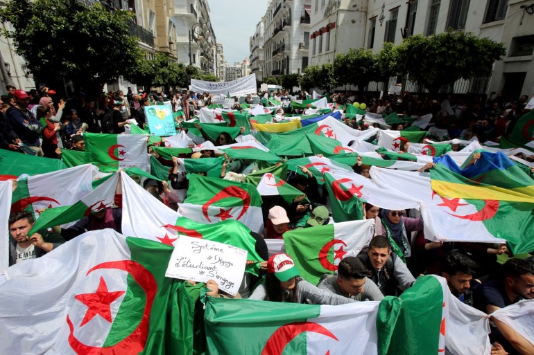 Demonstrators hold flags and banners during anti government protests in Algiers, Algeria April 23, 2019. The banner reads