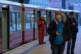 BERLIN, GERMANY - DECEMBER 10: People with smartphones stand next to an S-Bahn commuter train standing idle at a platform at Alexanderplatz during a strike by Deutsche Bahn workers on December 10, 2018 in Berlin, Germany. The strike, launched by the EVG labor union, shut down Deutsche Bahn's S-Bahn and Regio commuter rail services as well as long distance passenger and freight rail transport across Germany today for four hours in the early morning, forcing commuters to
