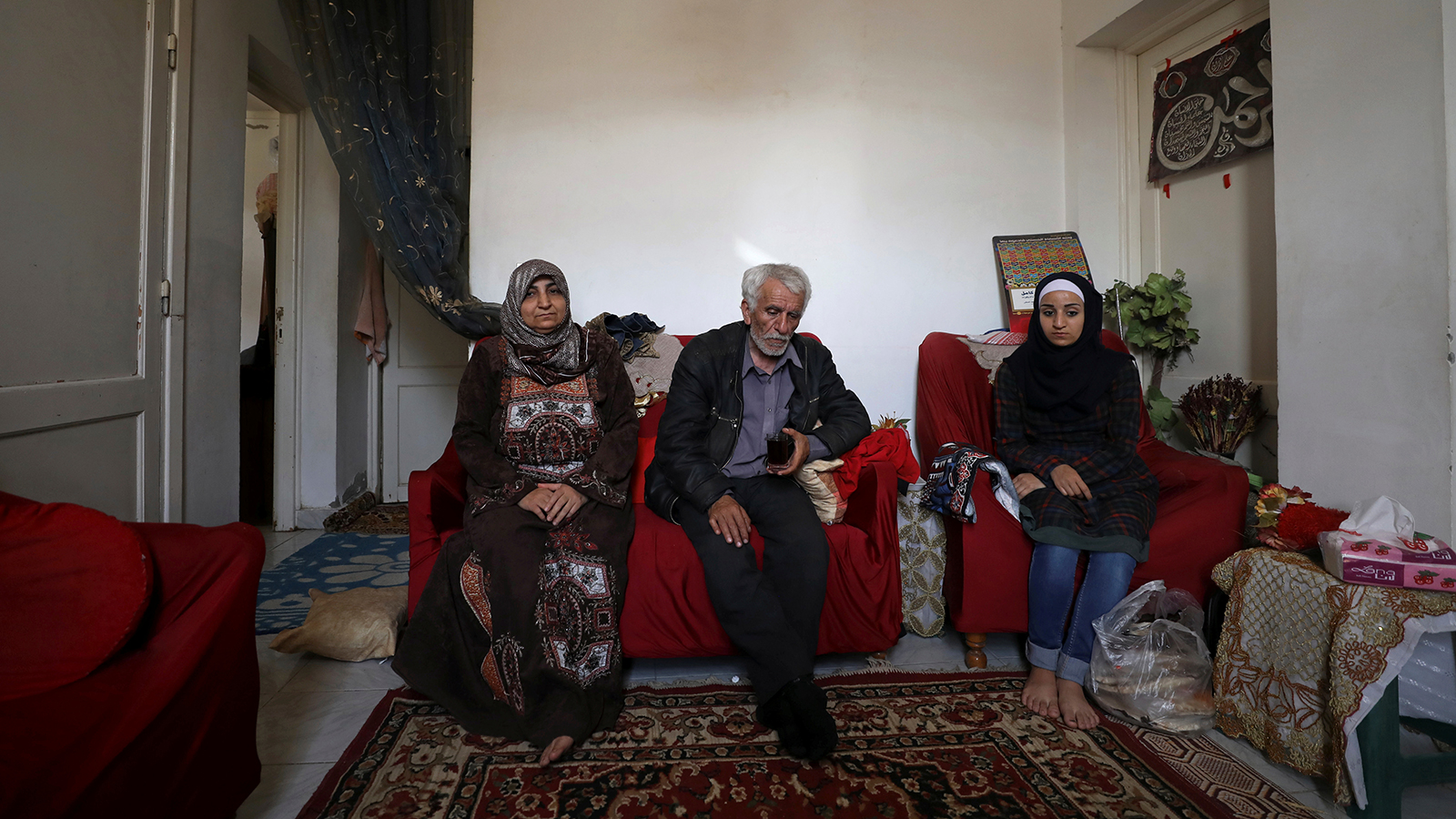 اللاجئ السوري أحمد الخطيب يجلس مع زوجته إلهام محمد وابنته ولاء في منزلهما بالقاهرة (رويترز)