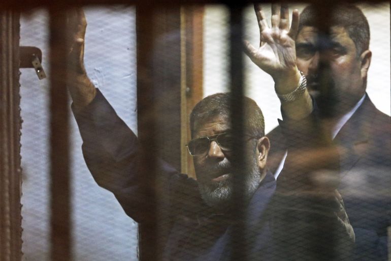 Deposed Egyptian President Mohamed Mursi greets his lawyers and people from behind bars after his verdict at a court on the outskirts of Cairo, Egypt June 16, 2015. An Egyptian court sentenced deposed President Mohamed Mursi to death on Tuesday on charges of killing, kidnapping and other offences during a 2011 mass jail break.The general guide of the Muslim Brotherhood, Mohamed Badie, and four other Brotherhood leaders were also handed the death penalty. More than 80 others were sentenced to death in absentia. REUTERS/Asmaa Waguih TPX IMAGES OF THE DAY