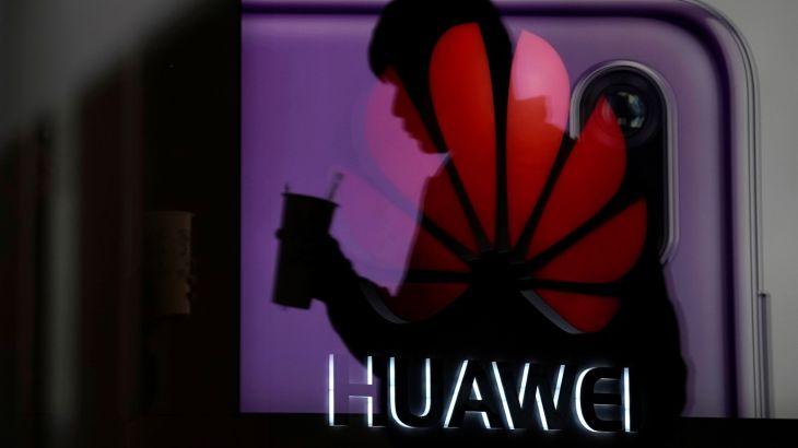 A man walking past a Huawei P20 smartphone advertisement is reflected in a glass door in front of a Huawei logo, at a shopping mall in Shanghai, China December 6, 2018. REUTERS/Aly Song