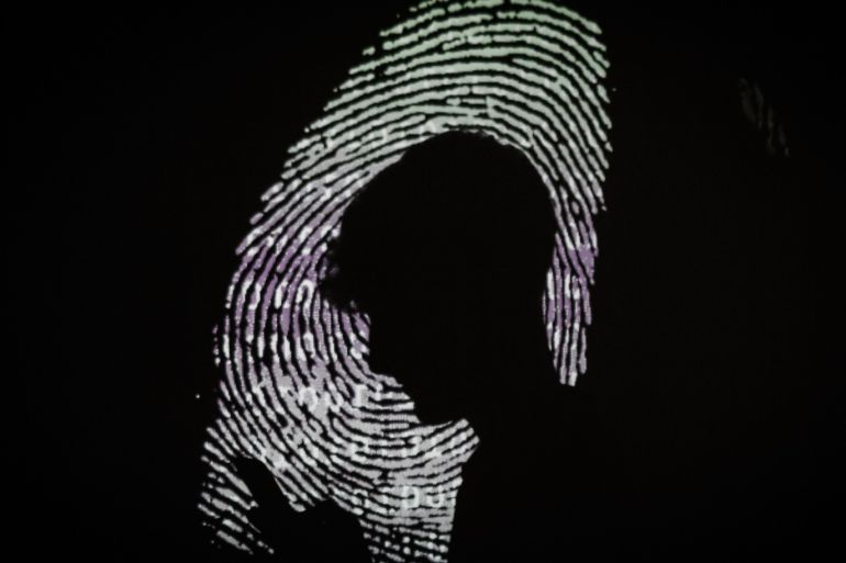 LONDON, ENGLAND - AUGUST 10: In this photo illustration, a man is seen using a mobile phone in the light of a projection of a thumbprint on August 09, 2017 in London, England. With so many areas of modern life requiring identity verification, online security remains a constant concern, especially following the recent spate of global hacks. (Photo by Leon Neal/Getty Images)