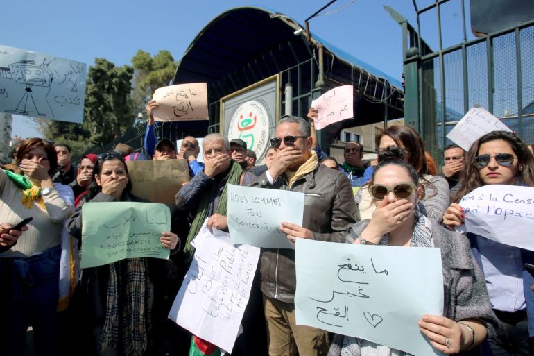 Journalists working at state media carry banners and cover their mouths during a protest in front of the state TV building to demand freedom to cover mass protests against President Abdelaziz Bouteflika, in Algiers, Algeria March 25, 2019. The banners read: