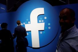 Attendees walk past a Facebook logo during Facebook Inc's F8 developers conference in San Jose, California, U.S., April 30, 2019. REUTERS/Stephen Lam