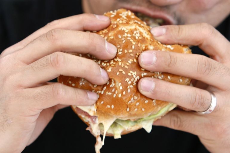 A man takes a bite from a hamburger in Hollywood, California October 3, 2007. REUTERS/Lucy Nicholson (UNITED STATES)