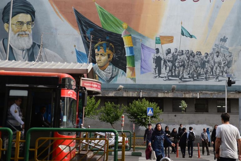 Daily life in Tehran - - TEHRAN, IRAN - MAY 22: Pedestrians pass in front of a political mural depicting Ruhollah Khomeini, founder of the Islamic republic of Iran, in Tehran, Iran on May 22, 2019.