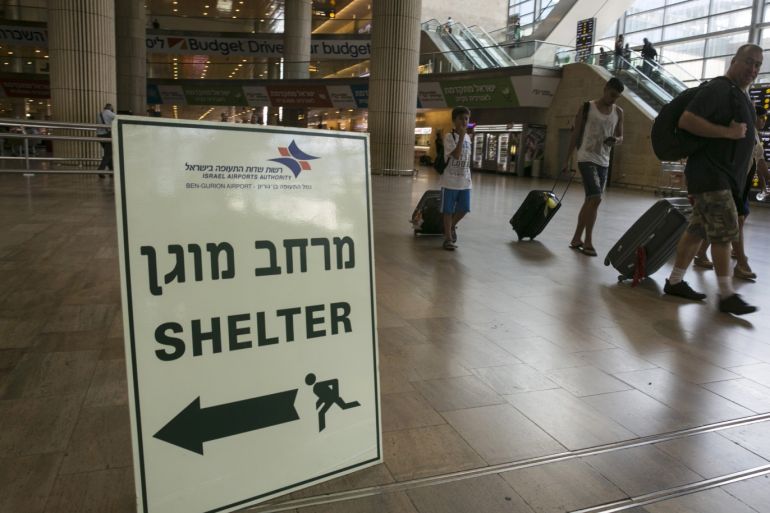 Passengers walk past a sign pointing to a shelter at Ben Gurion International airport, near Tel Aviv July 24, 2014. Israel won a partial reprieve from the economic pain of its Gaza war on Thursday with the lifting of a U.S. ban on commercial flights to Tel Aviv, as fighting pushed the Palestinian death toll over 700. A truce between the Jewish state and Hamas Palestinian fighters remained elusive despite intensive mediation bids. REUTERS/Baz Ratner (ISRAEL - Tags: POLITICS CIVIL UNREST CONFLICT TRANSPORT)