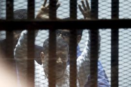 Ousted Egyptian President Mohamed Mursi gestures after his trial behind bars at a court in the outskirts of Cairo, April 21, 2015. An Egyptian court sentenced ousted President Mohamed Mursi to 20 years in prison without parole on Tuesday for the killing of protesters in December 2012, in a decision broadcast on state television. REUTERS/Amr Abdallah Dalsh TPX IMAGES OF THE DAY