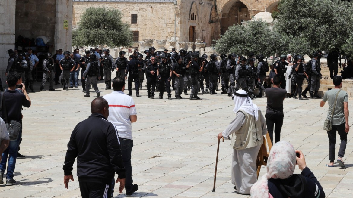 Palestinians stand near Israeli policemen as clashes erupted with Palestinians on
