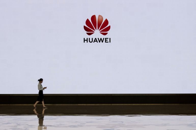 SHENZHEN, CHINA - APRIL 12: A member of Huawei's reception staff walks in front of a large screen displaying the logo in the foyer of a building used for high profile customer visits and displays at the company's Bantian campus on April 12, 2019 in Shenzhen, China. Huawei is Chinas most valuable technology brand, and sells more telecommunications equipment than any other company in the world, with annual revenue topping $100 billion U.S. Headquartered in the southern