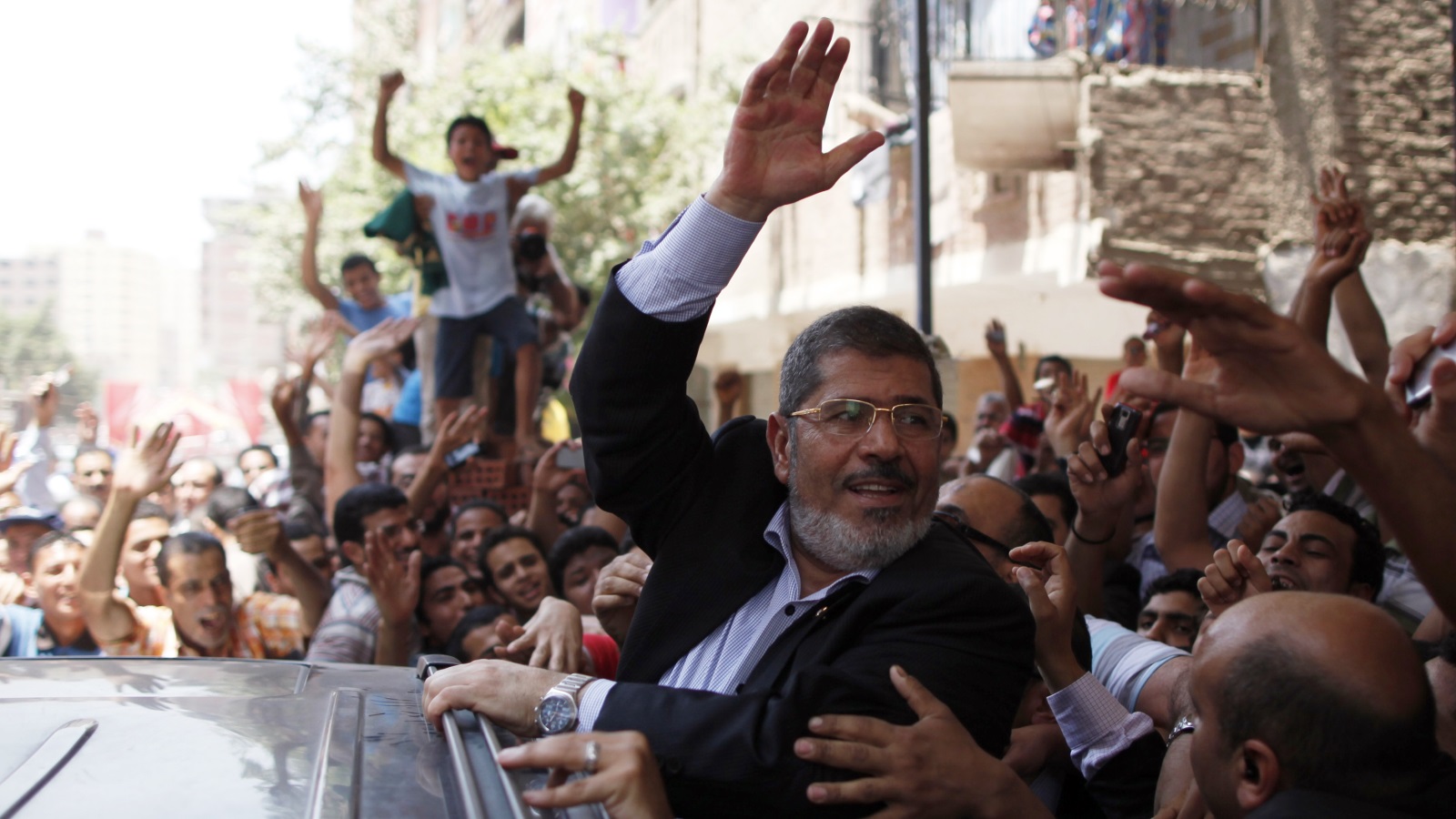 مرسي في إحدى جولاته يحيي الجماهير (رويترز)