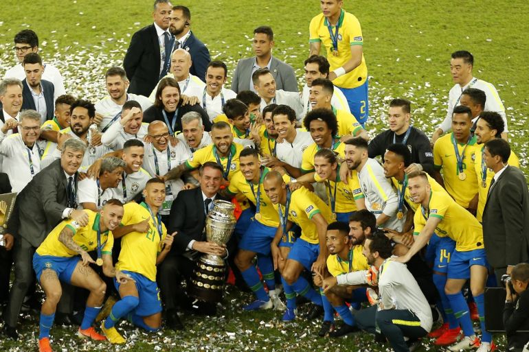 RIO DE JANEIRO, BRAZIL - JULY 07: President of Brazil Jair Bolsonaro, Dani Alves of Brazil and teammates pose with the trophy after winning the Copa America Brazil 2019 Final match between Brazil and Peru at Maracana Stadium on July 07, 2019 in Rio de Janeiro, Brazil. (Photo by Wagner Meier/Getty Images)
