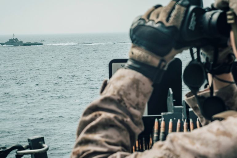 A U.S. Marine observes an Iranian fast attack craft from USS John P. Murtha during a Strait of Hormuz transit, Arabian Sea off Oman, in this picture released by U.S. Navy on July 18, 2019.. Donald Holbert/U.S. Navy/Handout via REUTERS ATTENTION EDITORS- THIS IMAGE HAS BEEN SUPPLIED BY A THIRD PARTY.