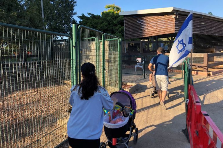 Visitors walk past an Israeli flag at a park in the northern Israeli town of Afula, July 13, 2019. Picture taken July 13, 2019. REUTERS/Rami Ayyub