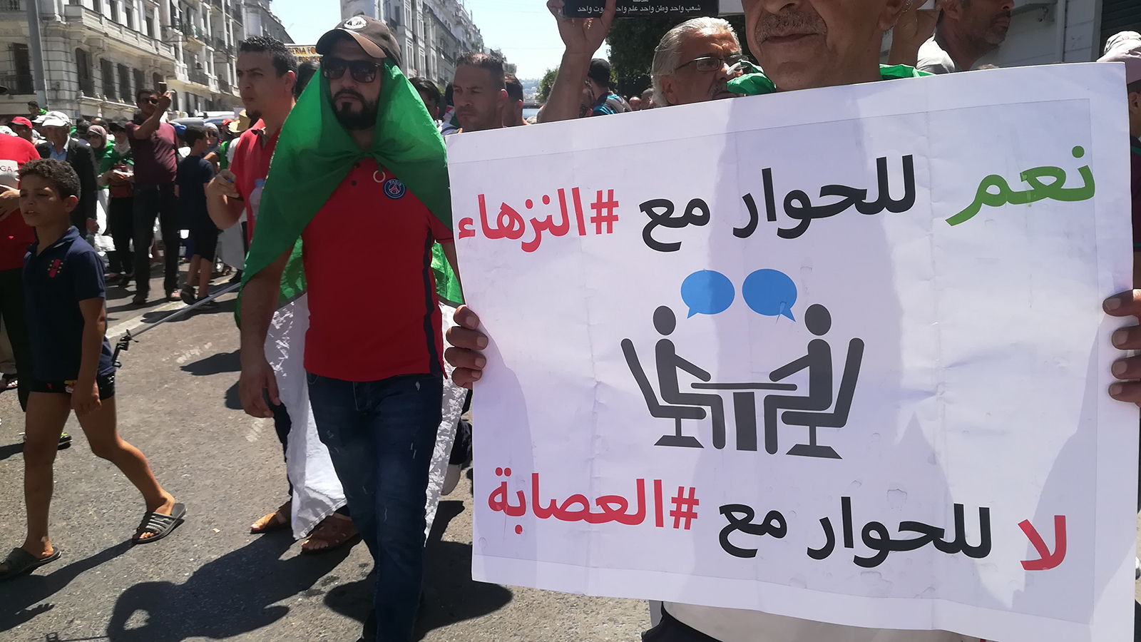 متظاهرون في وسط العاصمة يرفعون لافتة ترفض الجلوس على طاولة الحوار مع رموز نظام بوتفليقة (الجزيرة-أرشيف)