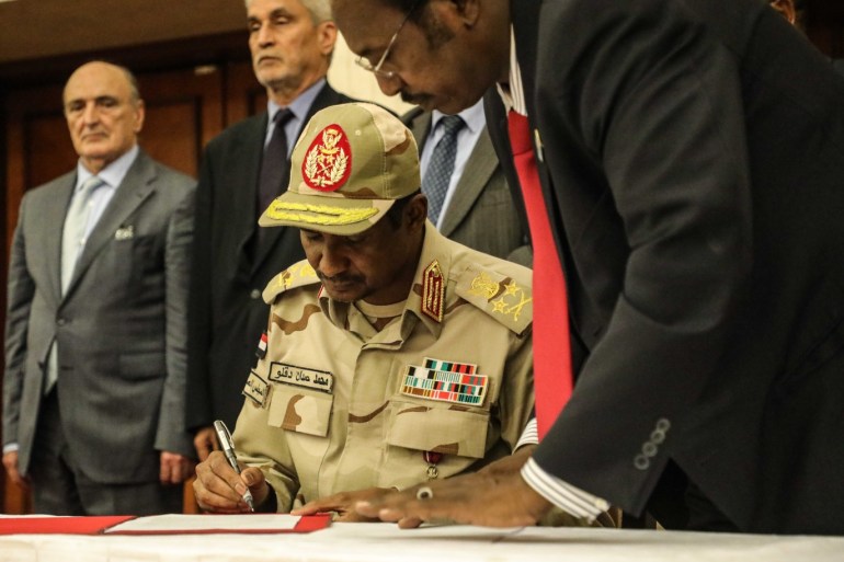 Sudan military rulers, opposition sign transition deal- - KHARTOUM, SUDAN - JULY 17 : Sudanese General and Vice President of Sudanese Transitional Military Council, Mohamed Hamdan Dagalo (C) inks an agreement in Khartoum on July 17, 2019. Sudan's ruling military council and a coalition of opposition groups on Wednesday signed a political deal that paves the way for the handover of power to a civilian administration. The signing of the deal came after marathon talks between the Transitional Military Council (TMC) and Forces of Freedom and Change coalition throughout the night to iron out some details of the accord.