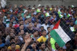 Palestinian spectators are pictured through a fence as they watch the first leg of Palestine Cup final soccer match between Gaza Strip's Shejaia and Hebron's Al-Ahly at al-Yarmouk stadium in Gaza City August 6, 2015. A Palestinian team from the Gaza Strip hosted West Bank opposition for the first time in 15 years on Thursday after Israel gave the visitors permission to cross its territory for the clash between the two lands' respective cup holders. The Gaza Strip's Shejaia and Al-Ahly from Hebron in the Israeli-occupied West Bank played in a fixture that appeared in doubt before the permit granted by Israel, whose territory separates Gaza and the West Bank. REUTERS/Suhaib Salem