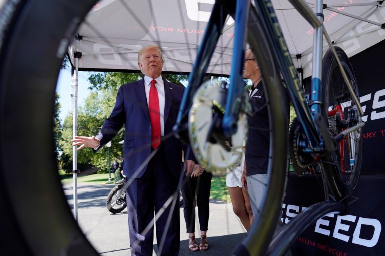 U.S. President Donald Trump Is seen through the wheel of a Litespeed Bicycles tire while examining products at the third annual