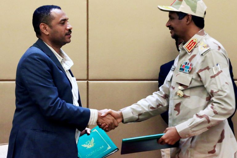 Deputy Head of Sudanese Transitional Military Council, Mohamed Hamdan Dagalo shakes hands with Sudan's opposition alliance coalition's leader Ahmad al-Rabiah as they exchange signed copies of the constitutional declaration during a signing ceremony in Khartoum, Sudan August 4, 2019. REUTERS/Mohamed Nureldin Abdallah