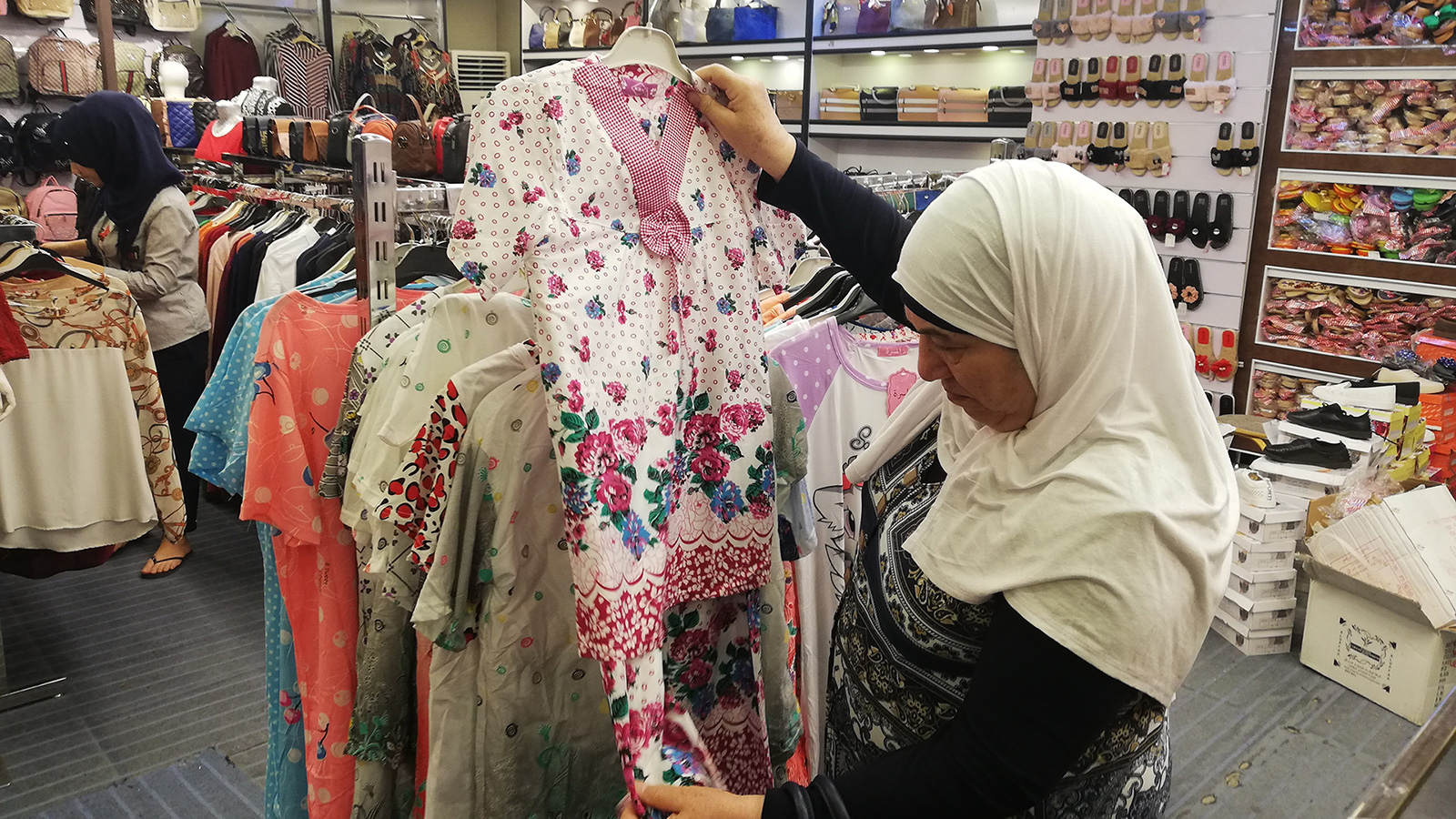 ‪الحاجة أم خالد في أحد المحلات تختار الملابس لليتيمات‬ (الجزيرة)