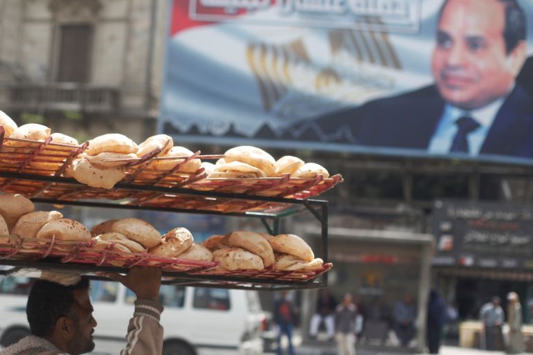 A man carries breads on his head along a busy street near a banner for Egypt's President Abdel Fattah al-Sisi from the campaign titled “Alashan Tabneeha” (So You Can Build It) after election results in Cairo, Egypt April 3, 2018. REUTERS/Amr Abdallah Dalsh