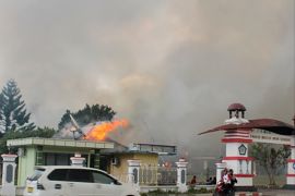 A car passes governor office building of Jayawijaya burned during a protest in Wamena, Papua, Indonesia, September 23, 2019 in this photo taken by Antara Foto. Antara Foto/Marius Wonyewun/ via REUTERS ATTENTION EDITORS - THIS IMAGE WAS PROVIDED BY A THIRD PARTY. MANDATORY CREDIT. INDONESIA OUT. BEST QUALITY AVAILABLE.