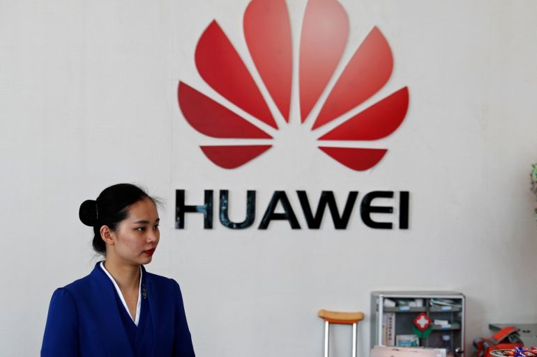 An employee stands next to the logo of Huawei in Shenzhen, Guangdong province, China March 29, 2019. REUTERS/Tyrone Siu