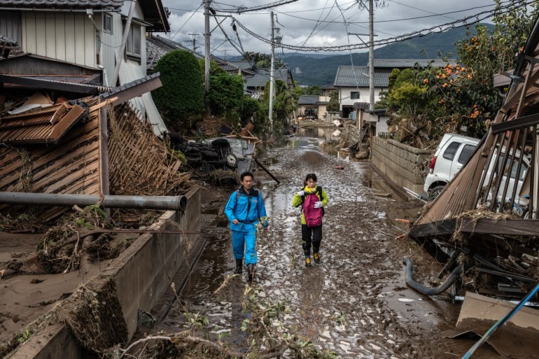NAGANO, JAPAN - OCTOBER 15: People walk past buildings that were destroyed by Typhoon Hagibis, on October 15, 2019 in Hoyasu near Nagano, Japan. Japan has mobilised over 100,000 rescue workers after Typhoon Hagibis, the most powerful storm in decades, swept across the country killing 66 people and leaving thousands injured and homeless. (Photo by Carl Court/Getty Images)