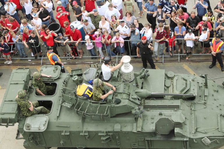 Pittsburgh Penguins Captain Sidney Crosby holds the Stanley Cup while sitting on the turret of a Canadian army Light Armored Vehicle (LAV) as he departs te jetty at CFB Halifax, Nova Scotia. August 7, 2009. Crosby had chosen his 22nd birthday as his tour day for the Stanley Cup. REUTERS/Paul Darrow (CANADA SPORT ICE HOCKEY)