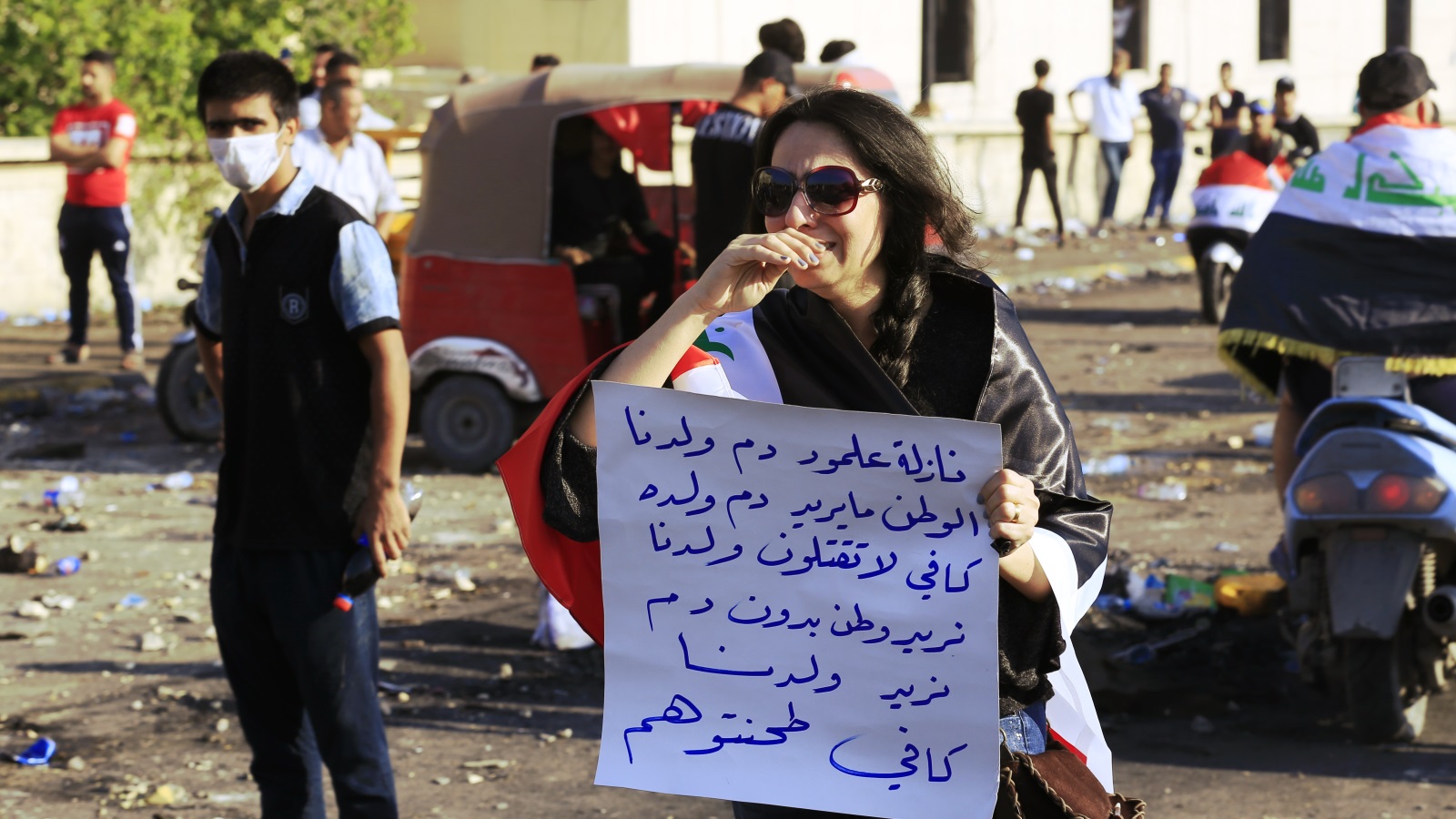 عراقية تشارك في الاحتجاجات ببغداد وترفع لوحة للتعبير عن رفض استخدام العنف ضد المتظاهرين (الأناضول)