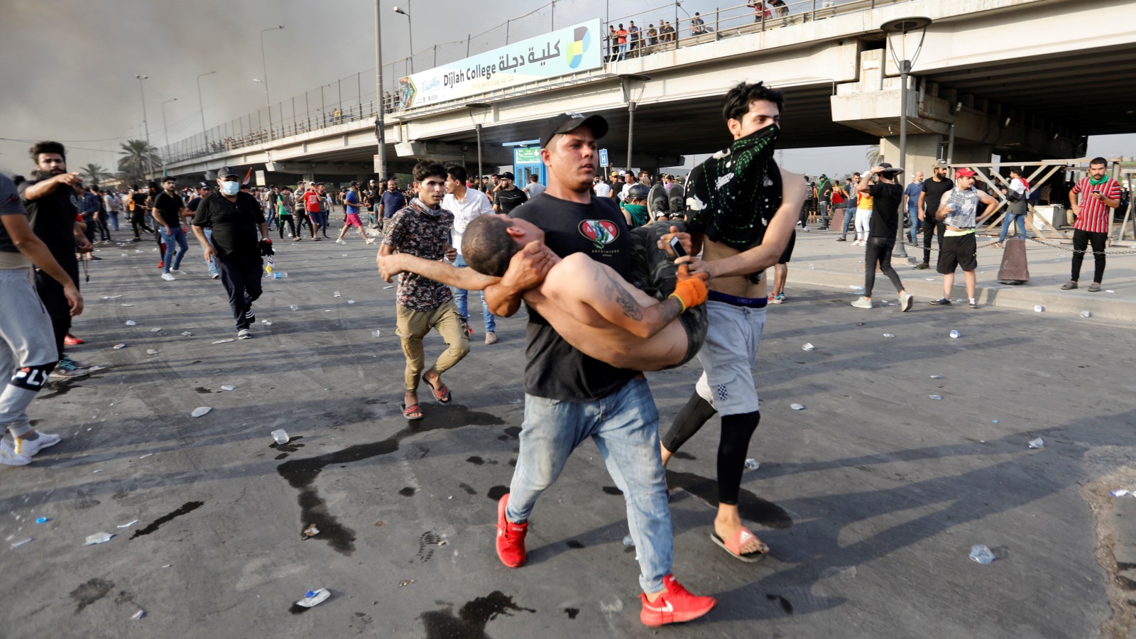‪متظاهرون يحملون زميلا لهم بعد إصابته في بغداد‬ (رويترز)