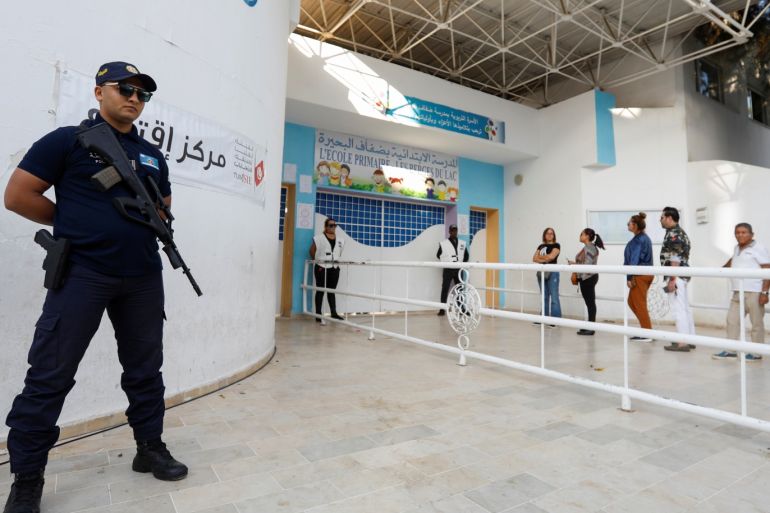 A police officer stands guard as people queue to cast their vote outside a polling station during a second round runoff of a presidential election in Tunis, Tunisia October 13, 2019. REUTERS/Zoubeir Souissi