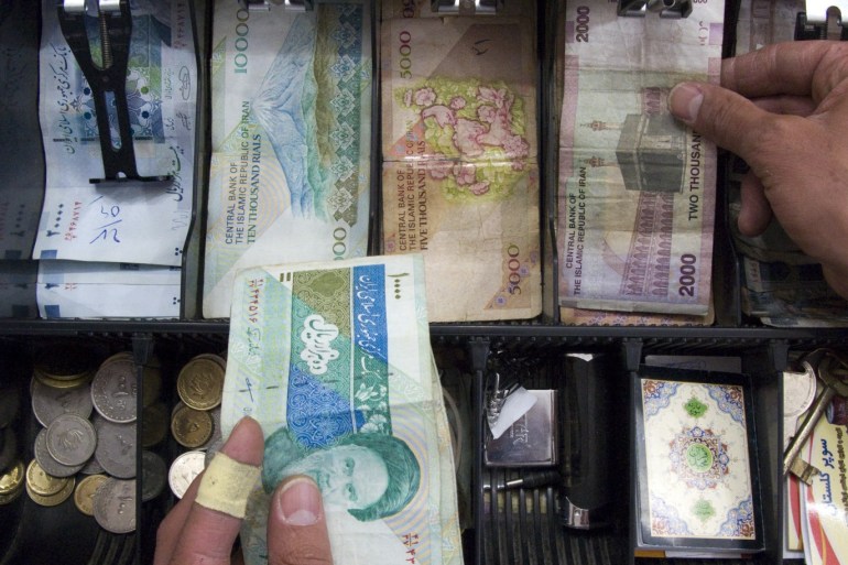 A storekeeper places money in the drawer of the cash register at his shop in Tehran May 4, 2008. With Western banks cutting ties with the Islamic Republic, it is becoming more and more difficult to transfer funds to the country of 70 million people. Tehran's increasing financial isolation is forcing some to bring in money by hand in thick wads of $100 bills on the plane from Dubai, the Gulf's financial centre, or elsewhere. REUTERS/Morteza Nikoubazl (IRAN)