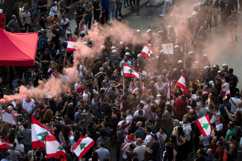 Demonstrators shout slogans as they stand next to a riot police cordon during ongoing anti-government protests in downtown Beirut